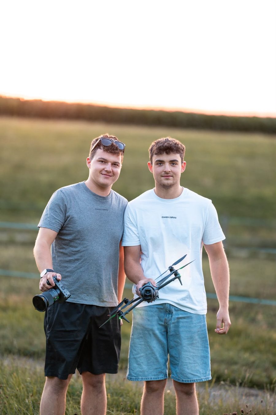 Simon und Laurin mit Kamera und Drohne auf dem Feld bei Sonnenuntergang