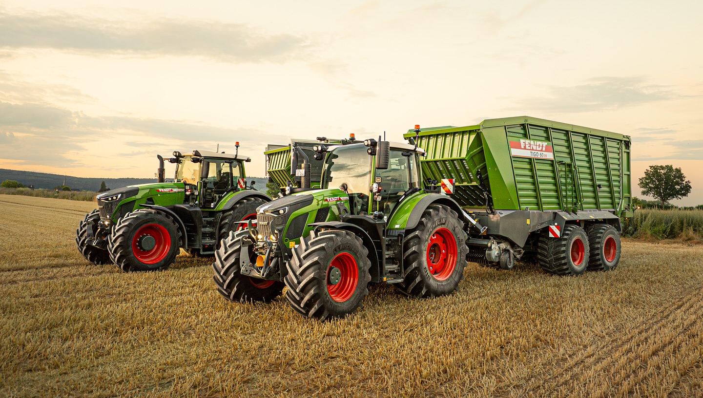 Zwei Fendt-Traktoren mit Ladewagen bei Sonnenuntergang